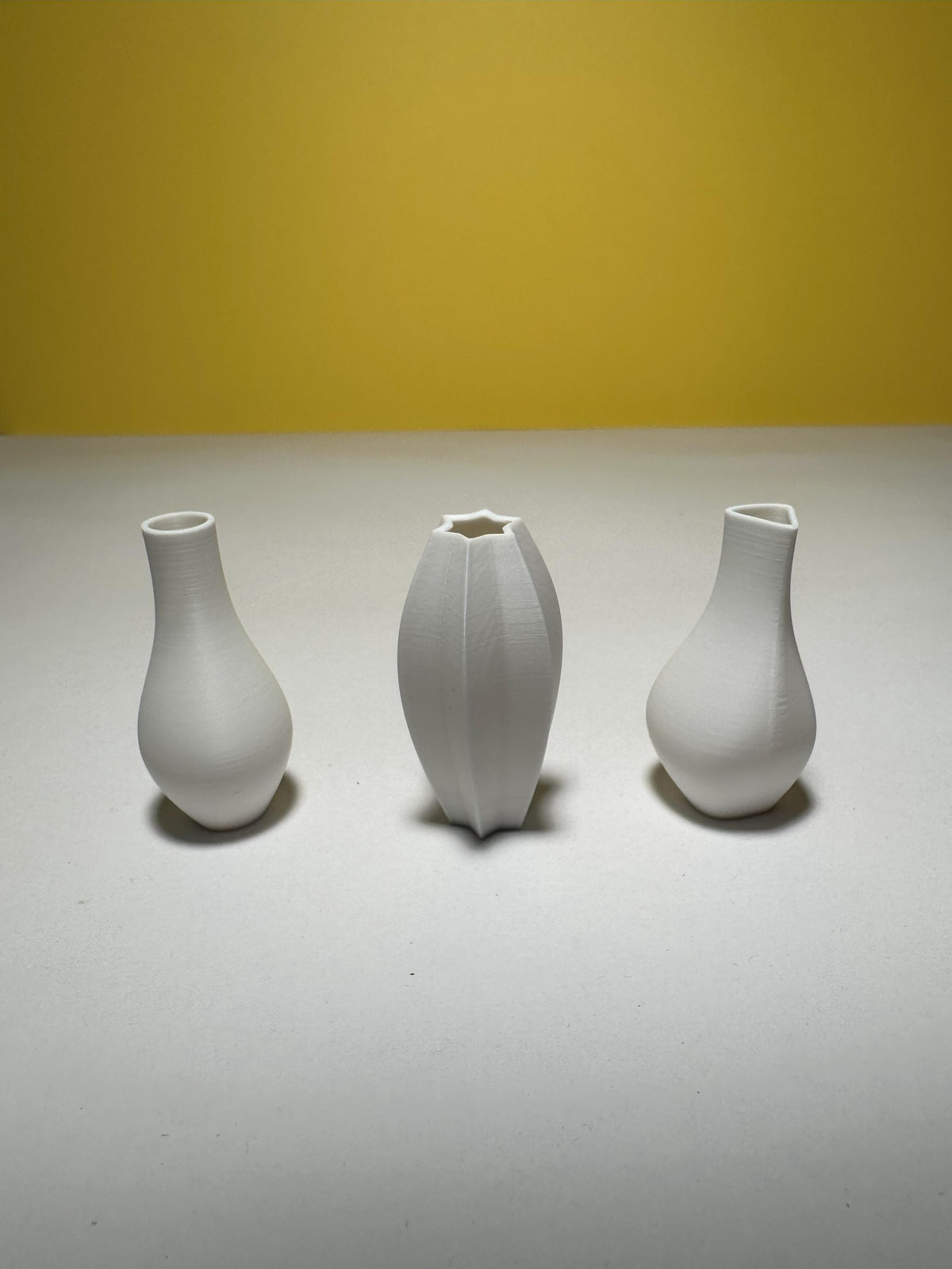 Three white sculptural dollhouse vases with a smooth matte finish